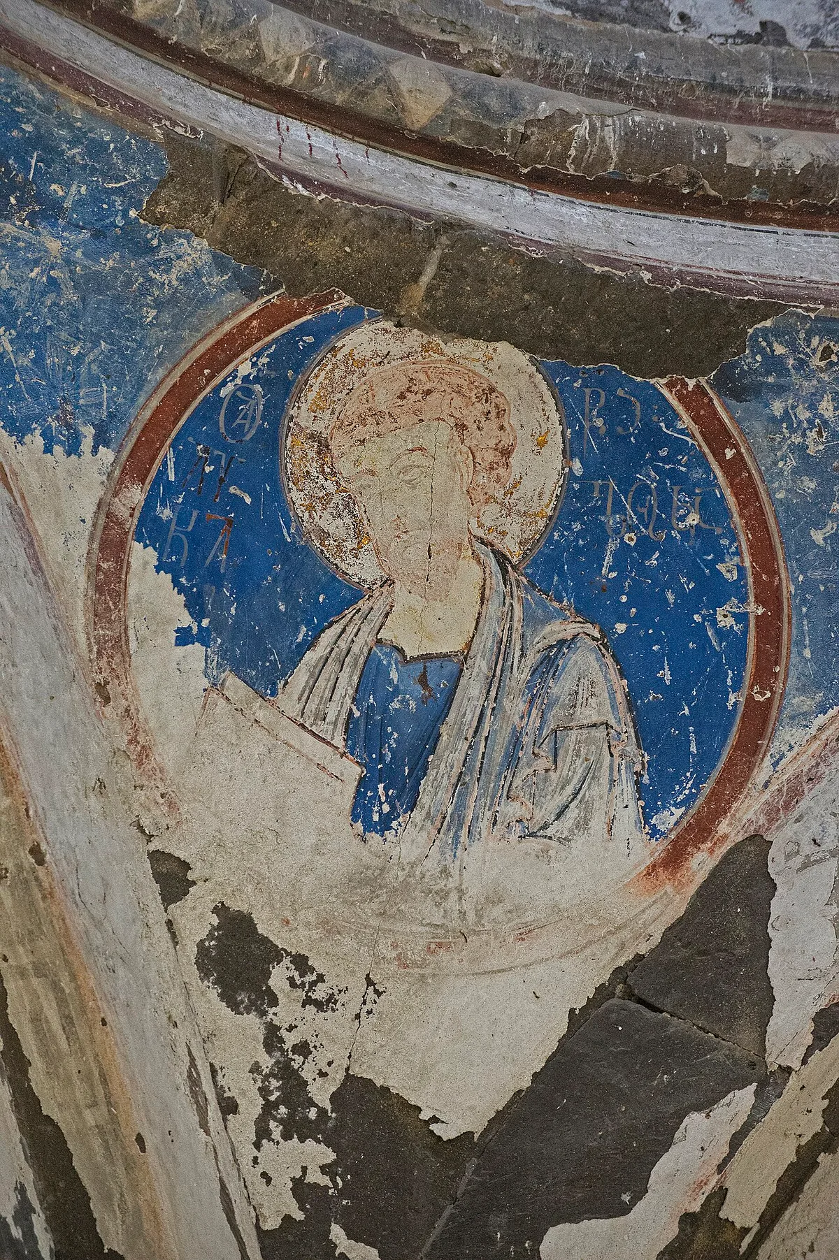 Een verbleekt fresco-medaillon met een evangelist in de kerk van Tigran Honents bij Ani: de blauwe ondergrond is grotendeels weggesleten en het pleisterwerk vertoont gaten en scheuren.