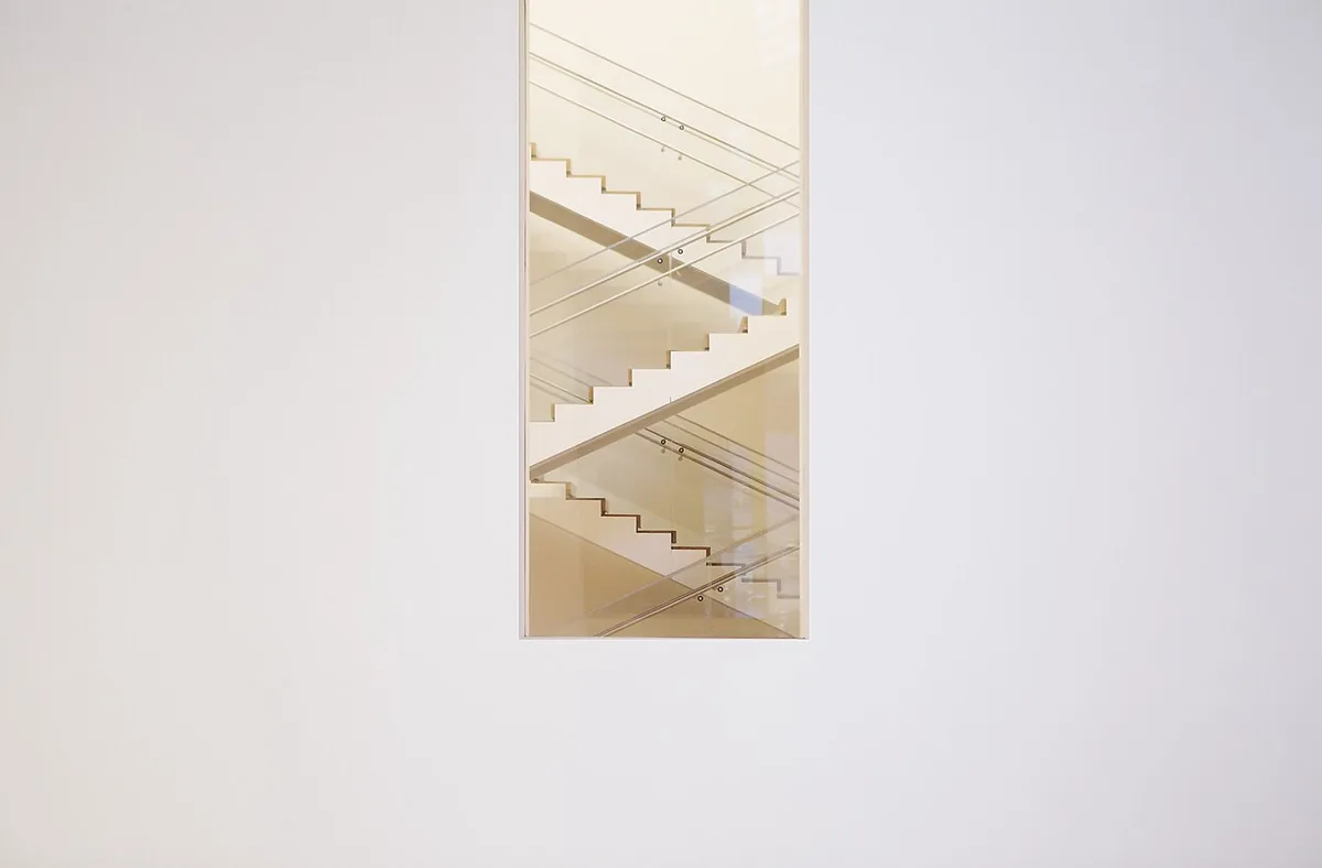 Een groot wit gepleisterd museumvlak waarop één klein ingelijst werk hangt, met veel lege muur eromheen.