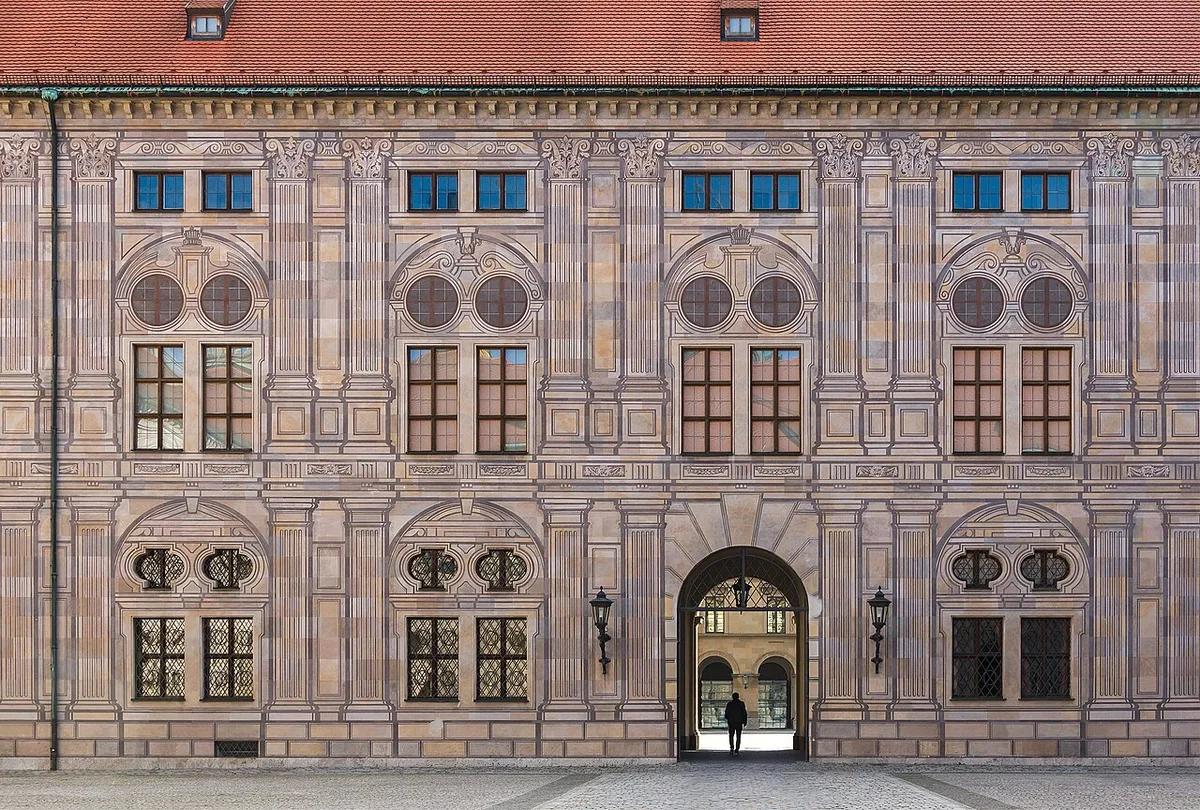 De gevel van de Keizerhof van de Residenz in München, waarop pilasters, vensteromlijstingen en blokwerk volledig zijn geschilderd op een verder vlakke muur.